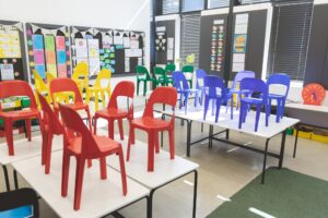 Front view of color chairs arranged on table in empty classroom at school