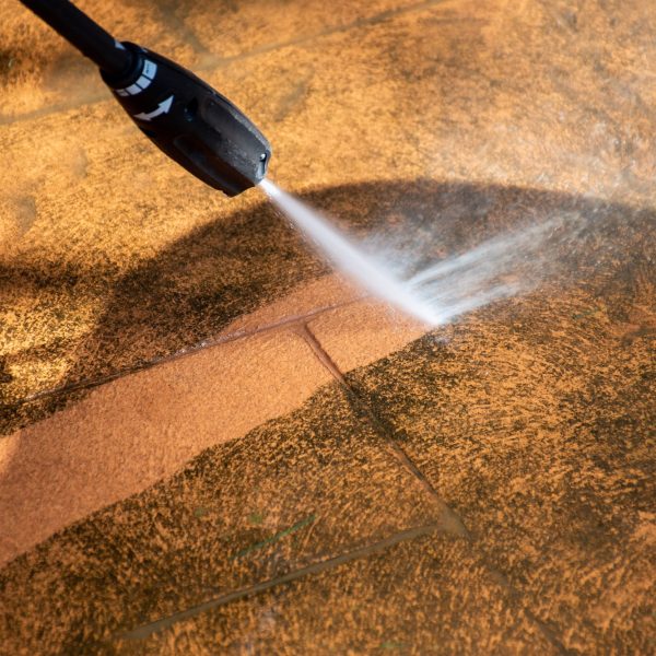 Washing the backyard tiles with high pressure cleaner